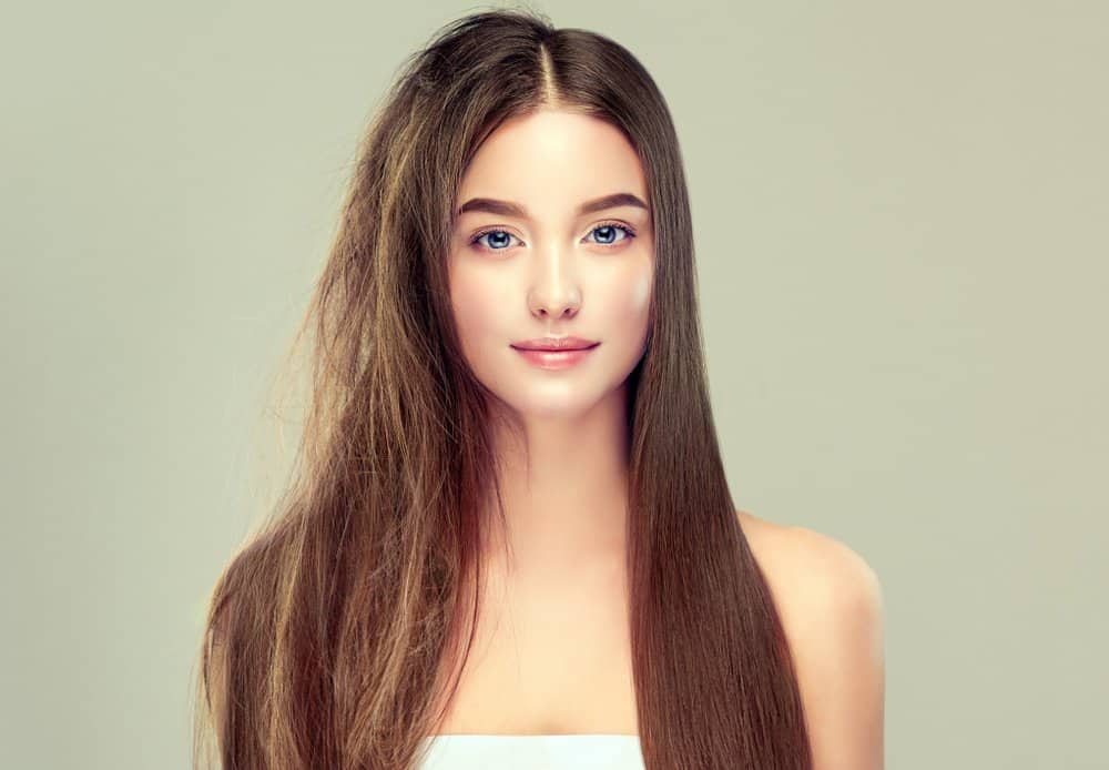 A long-haired woman with half her hair frizzy, half perfectly smooth