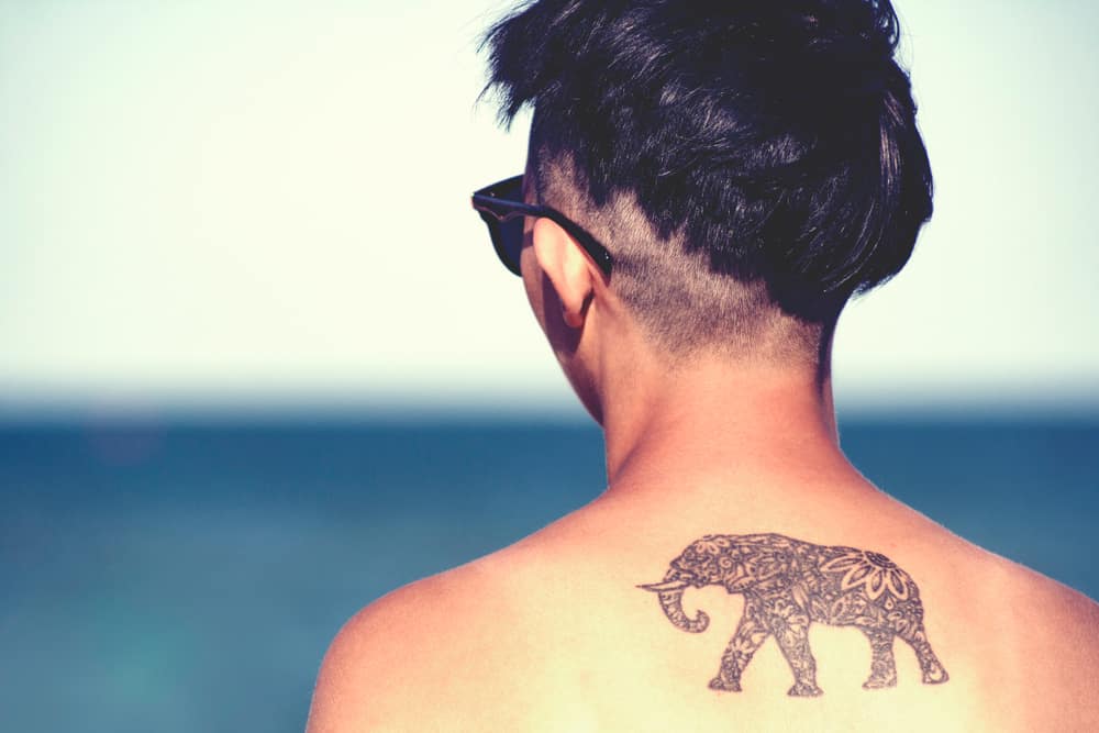 a man with an elephant tattoo on a beach