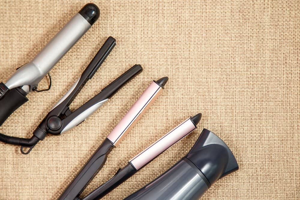 A collection of professional hair styling tools, including a hair straightener and hairdryer