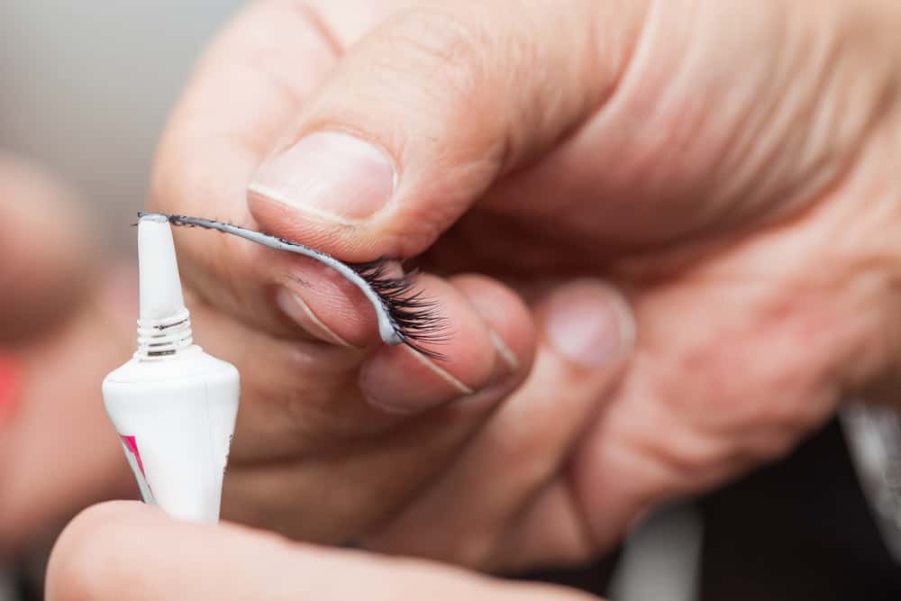 clear eyelash glue getting applied onto fake eyelashes