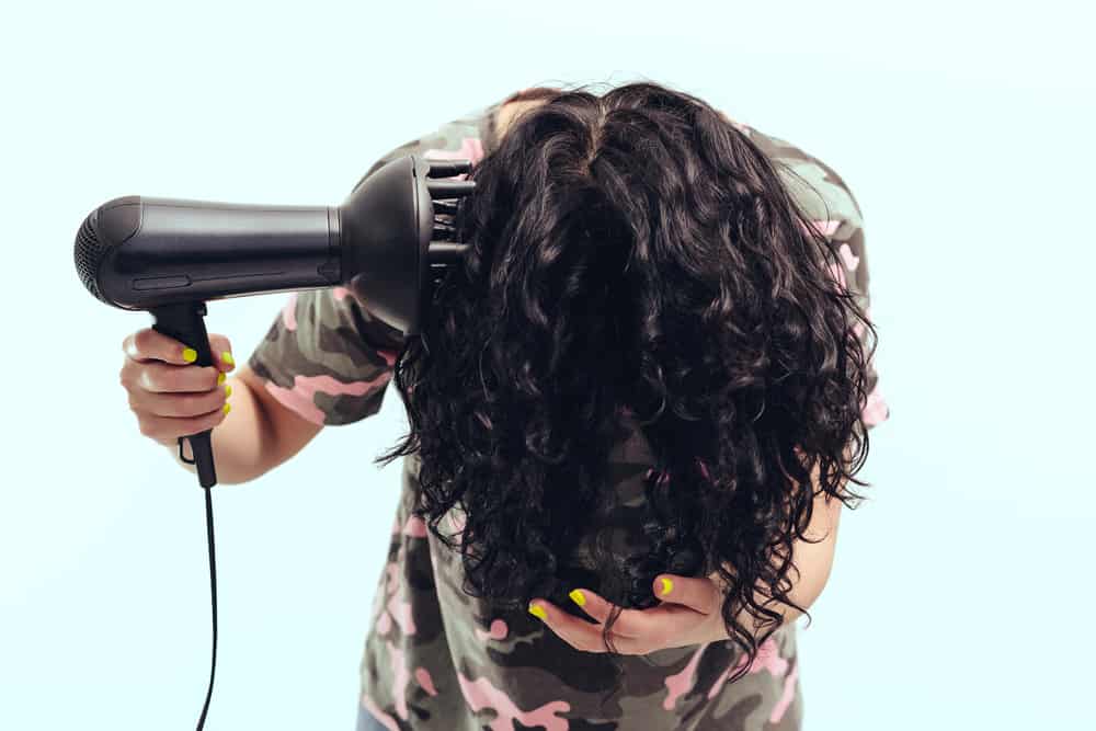 woman using a diffuser to dry her hair