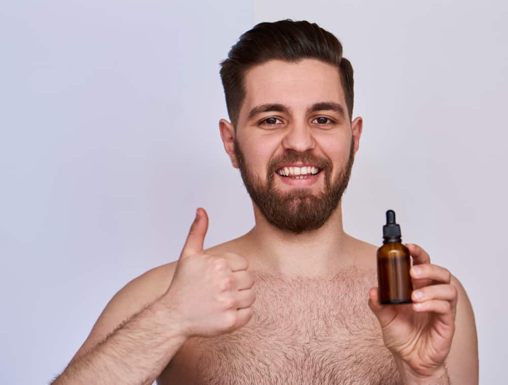 man holding a small bottle of beard oil