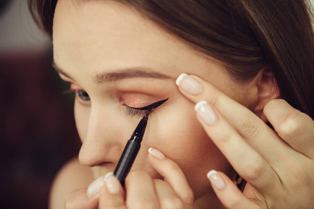 woman applying eyeliner on her eye