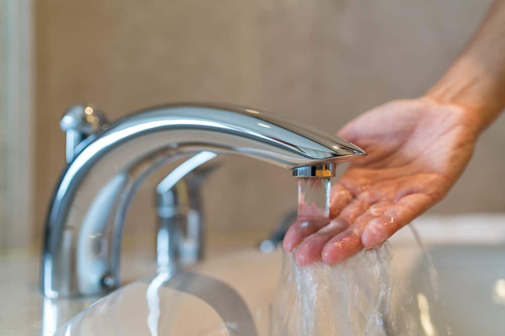  woman checking water temperature from tap