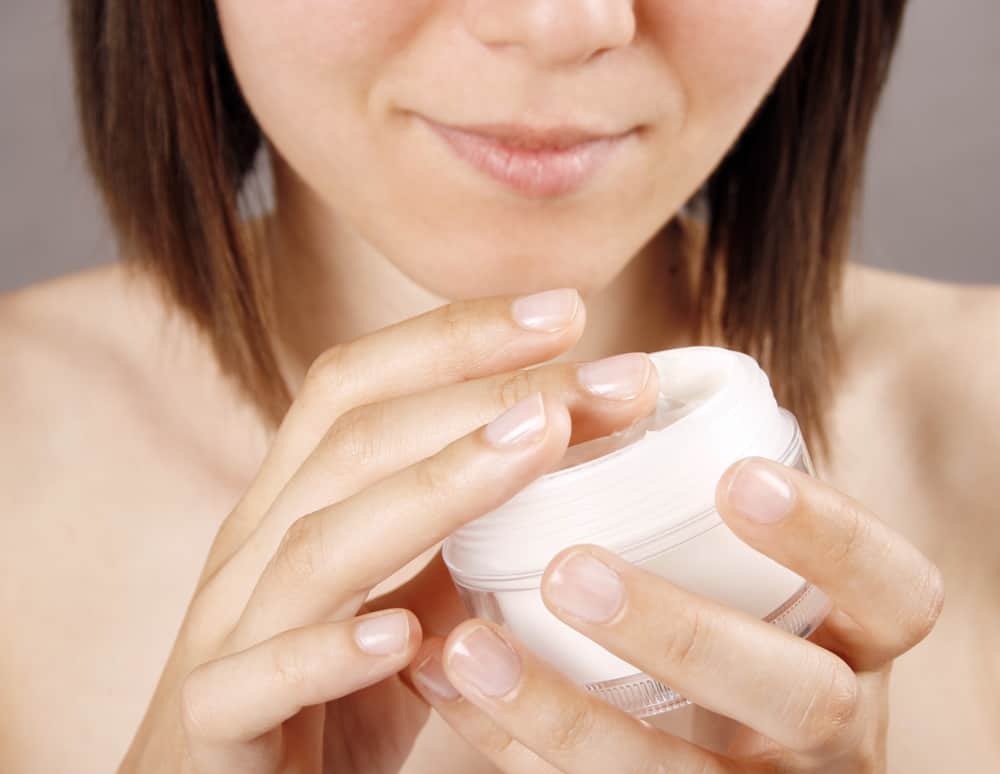 Young woman holding tub of moisturizing cream