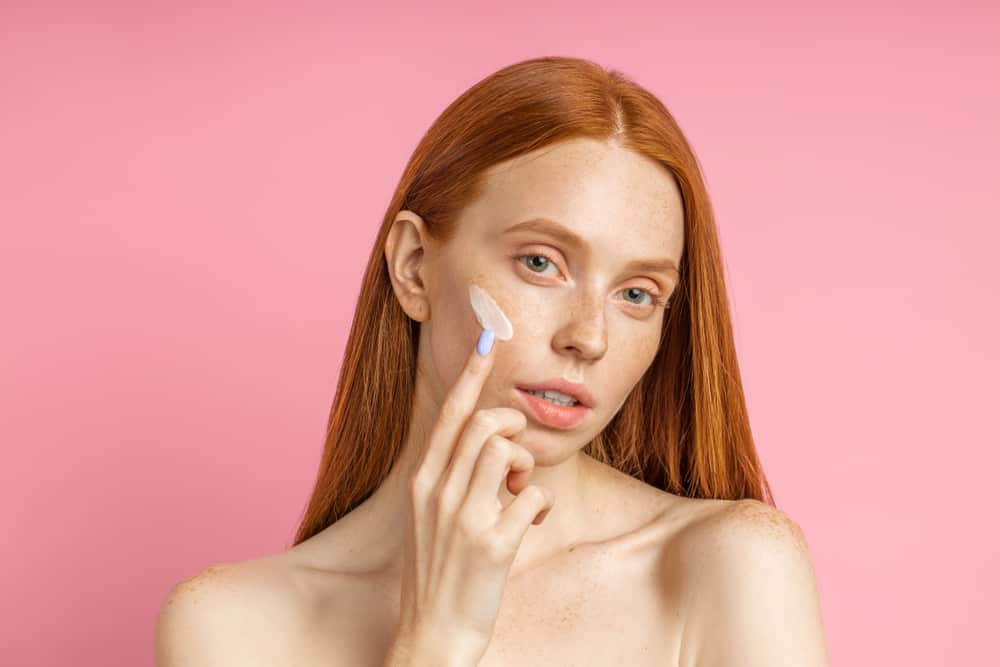 woman applying primer on cheekbones