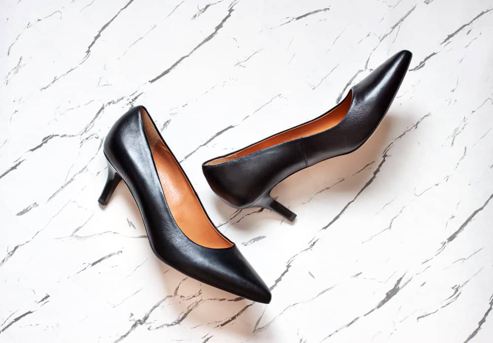 black kitten heel pumps on a white marble floor