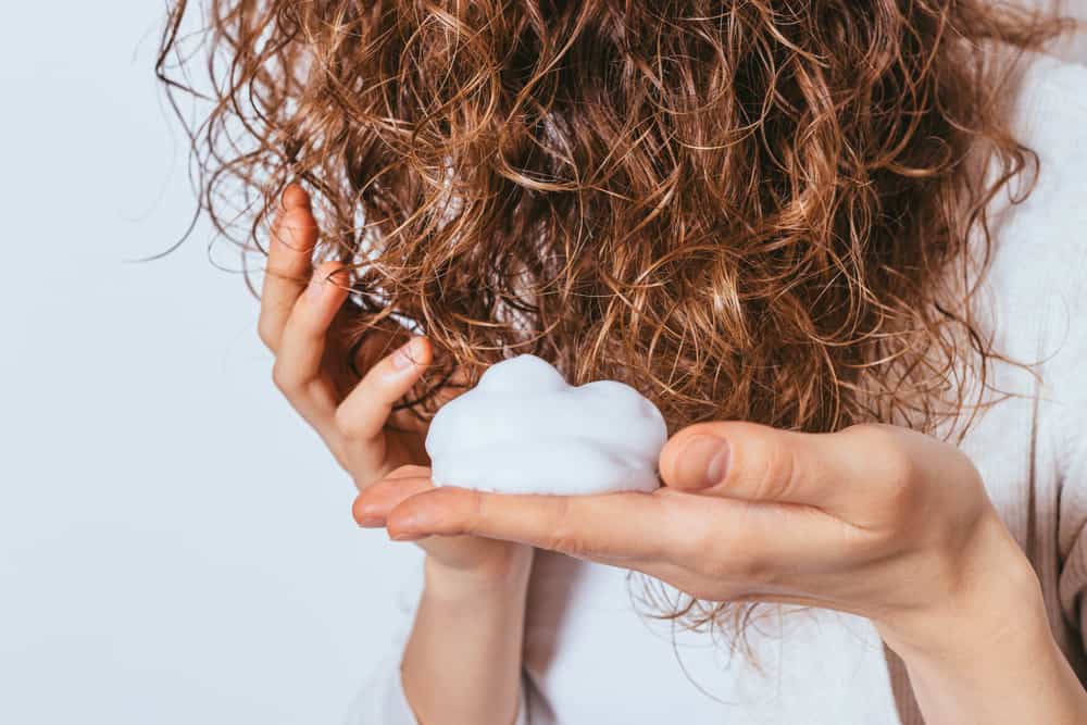 woman styling hair with mousse