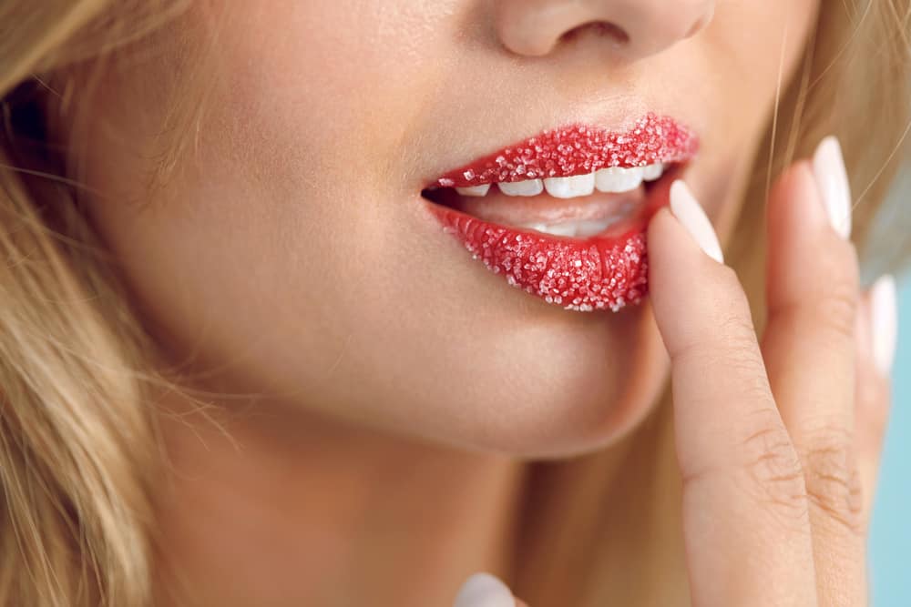 woman applying lip scrub onto her red lips
