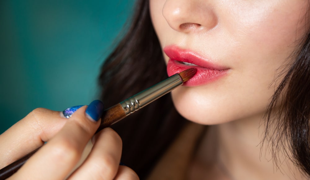 makeup artist applied lip tint on woman using brush