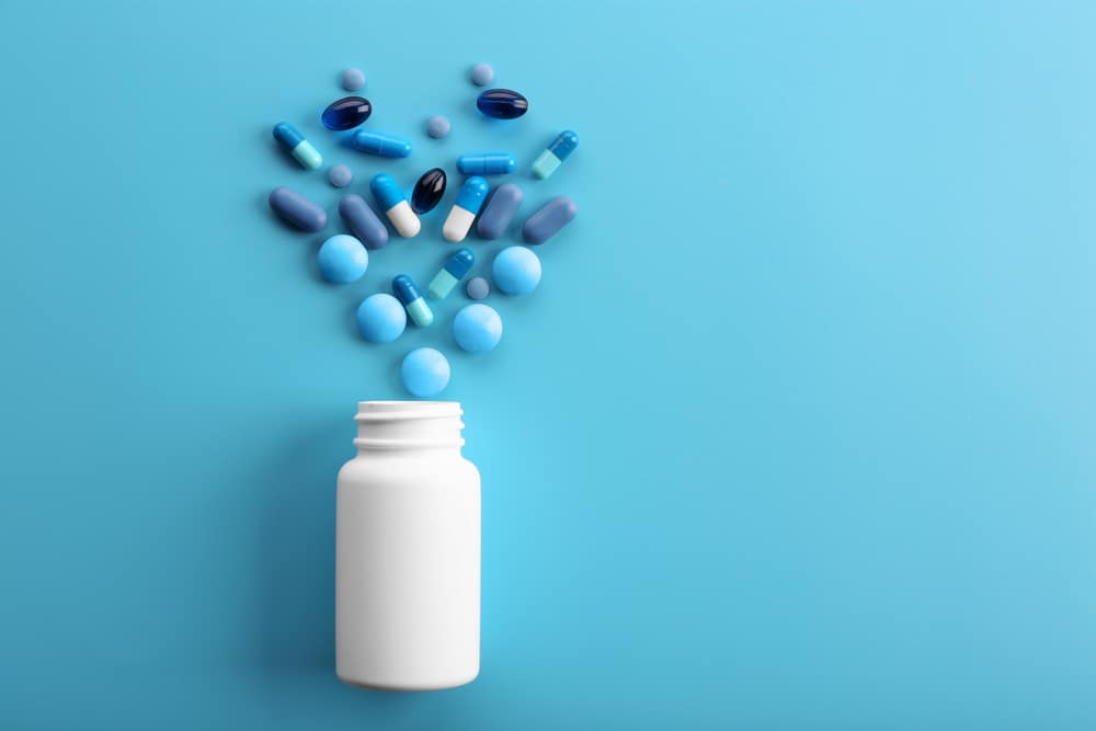 heart-shaped spill of blue pills from white bottle