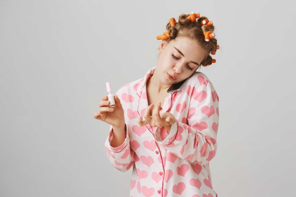 woman in pajamas painting nails white