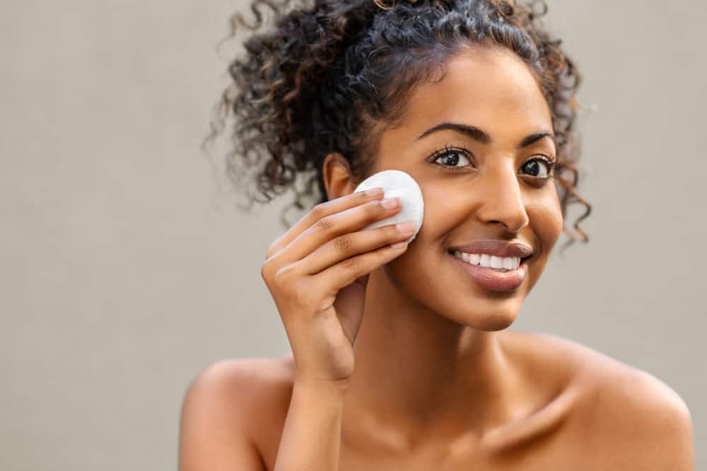 woman smiles while removing makeup