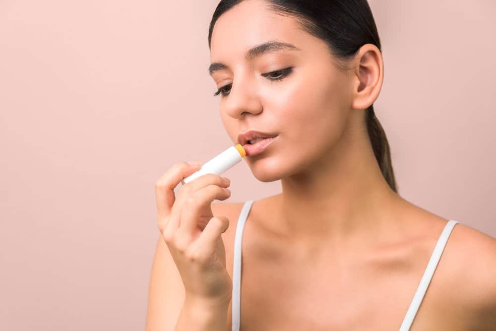 young woman applying yellow lip balm