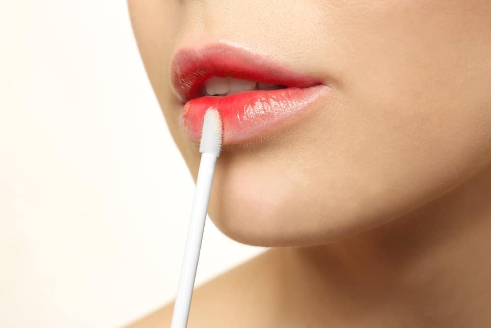 woman applying tinted lip gloss