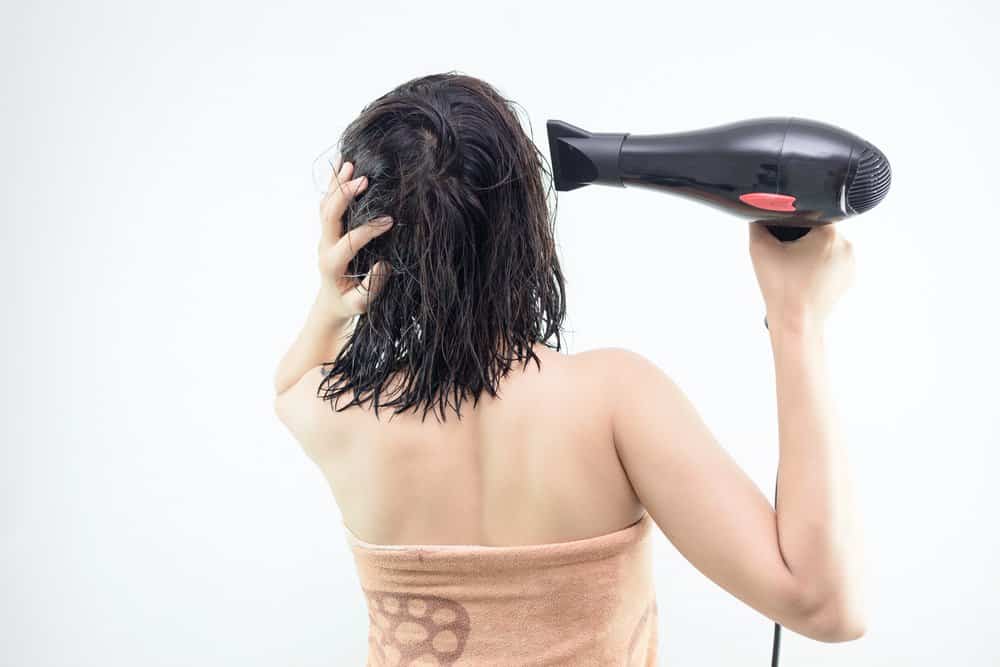 woman blow drying wet hair