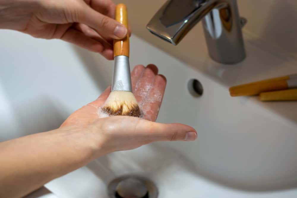 woman washing makeup brush