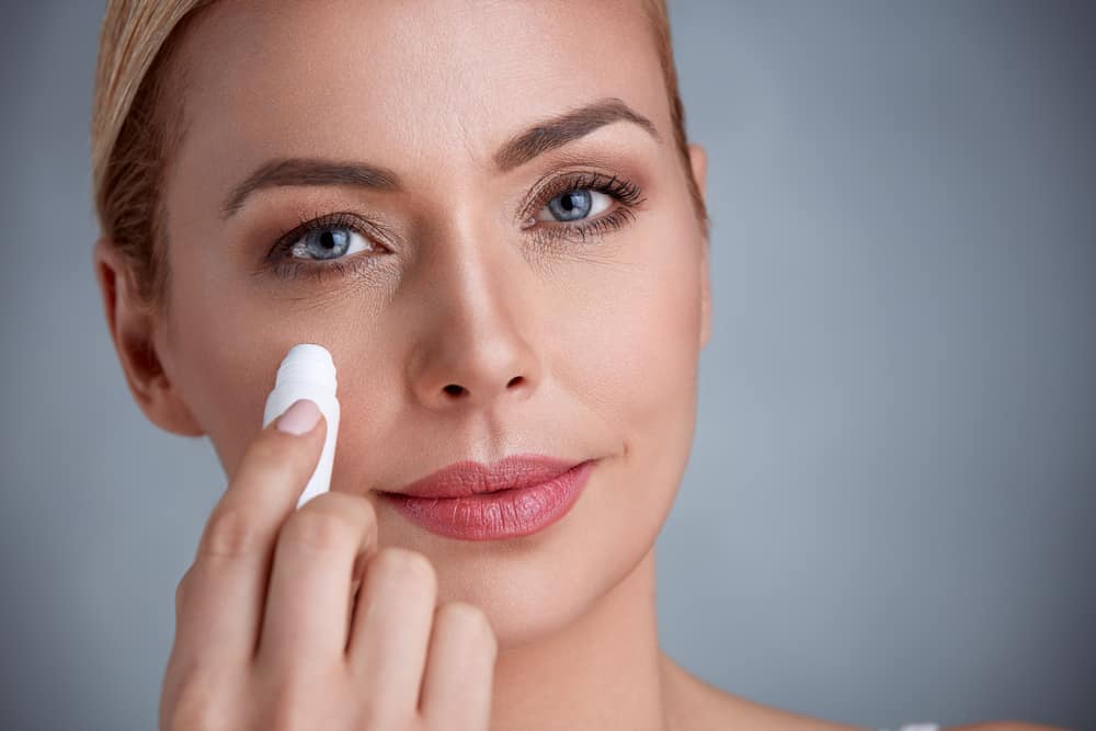 woman applying concealer to undereye circles