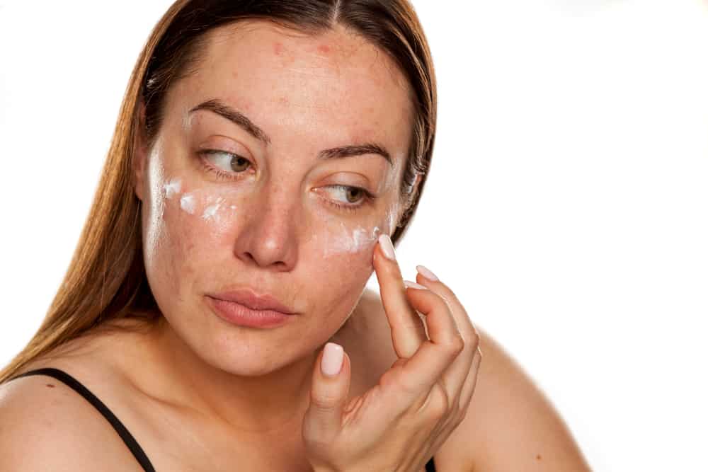 woman applying cream to face