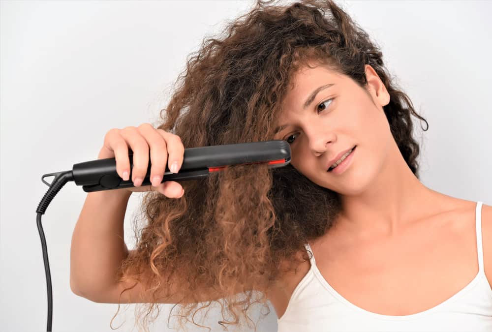 woman with curly hair and flat iron