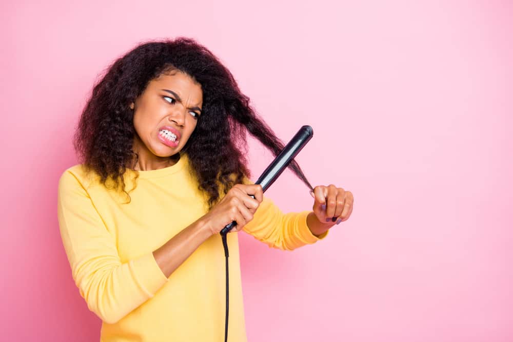 African American woman straightening hair