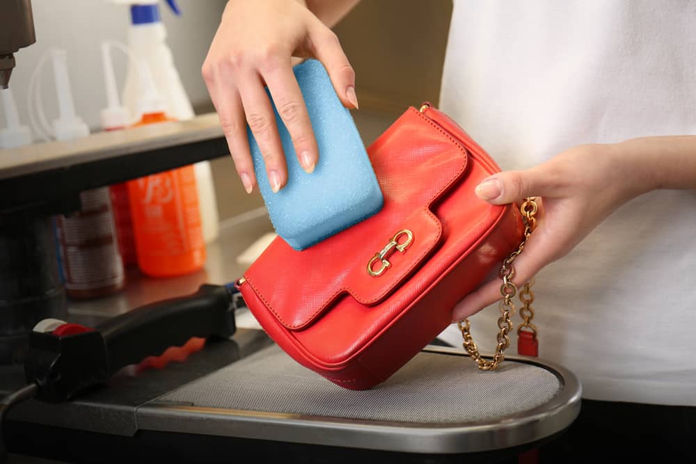 woman cleaning bag with sponge