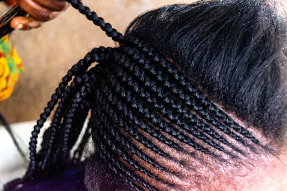 hairstylist braiding woman’s hair