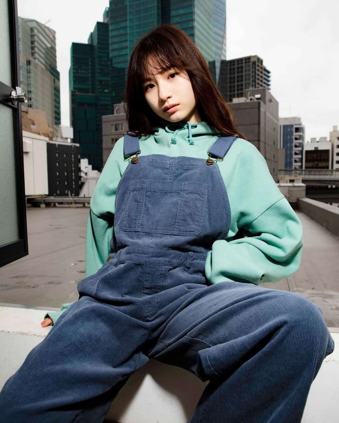 Young woman in pastel hoodie and denim overalls