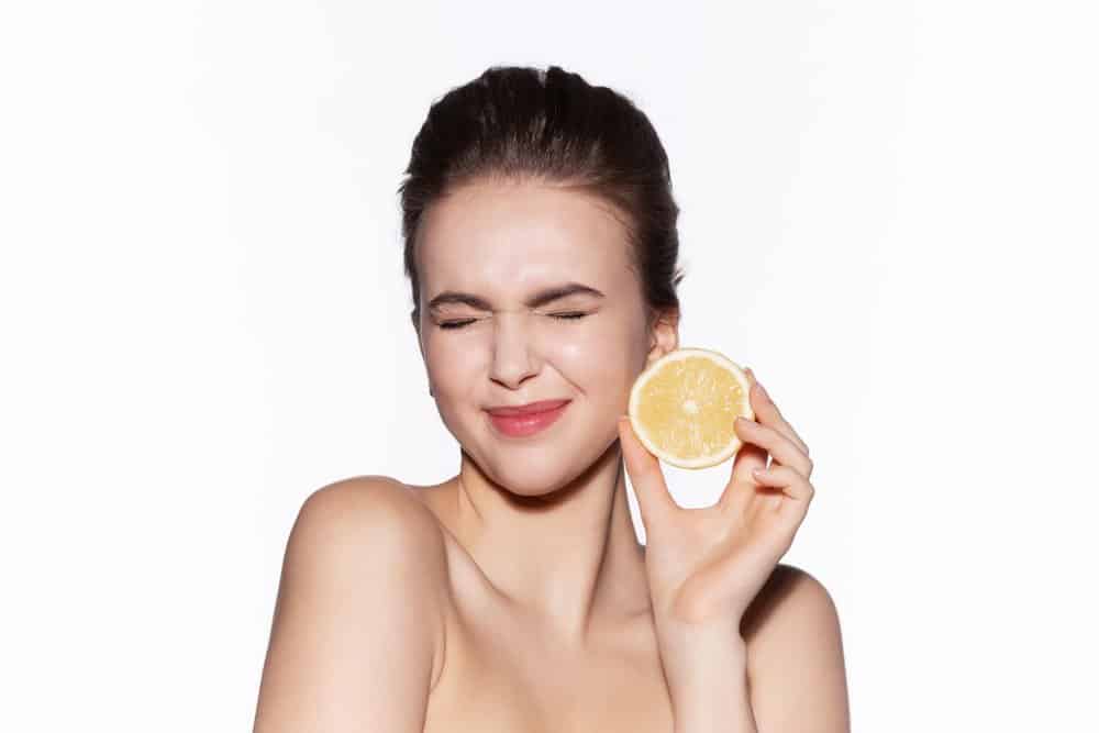 a woman holding up half a lemon