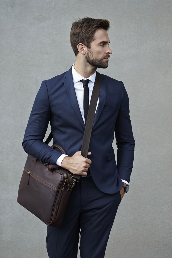 man in suit holding a satchel bag