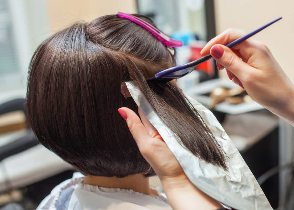 stylist applying bleach to brown hair