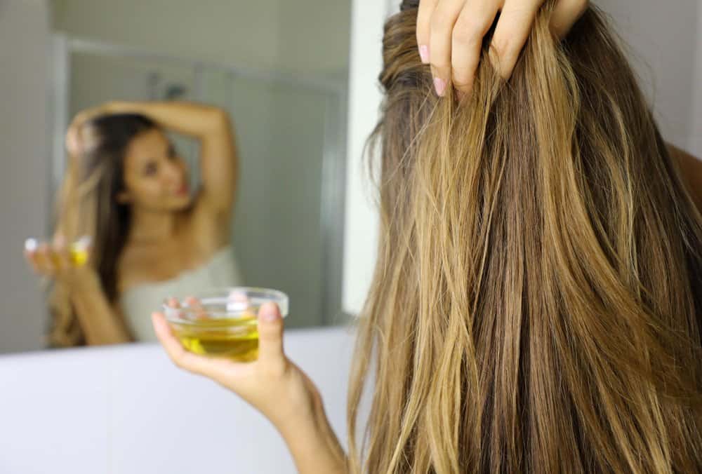 woman applying oil to hair