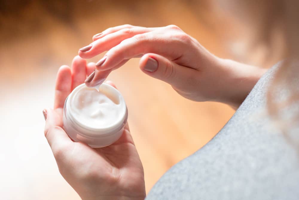 woman using face moisturizer