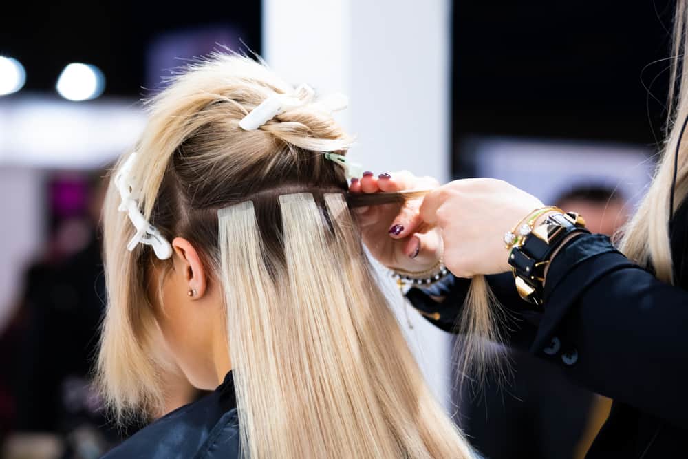 hairdresser applying hair extensions