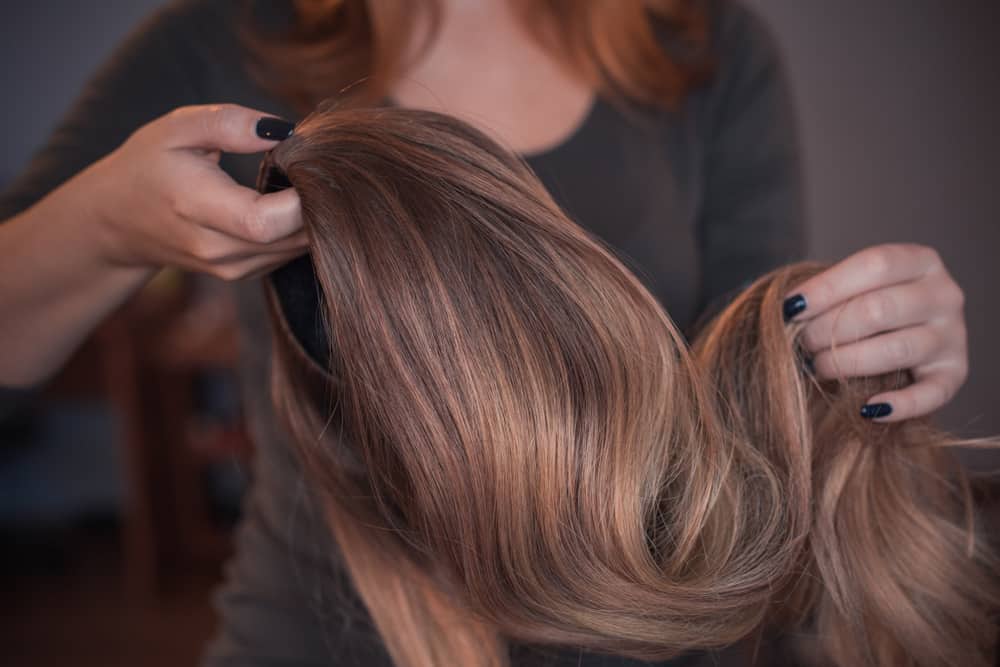 woman holding brown wig