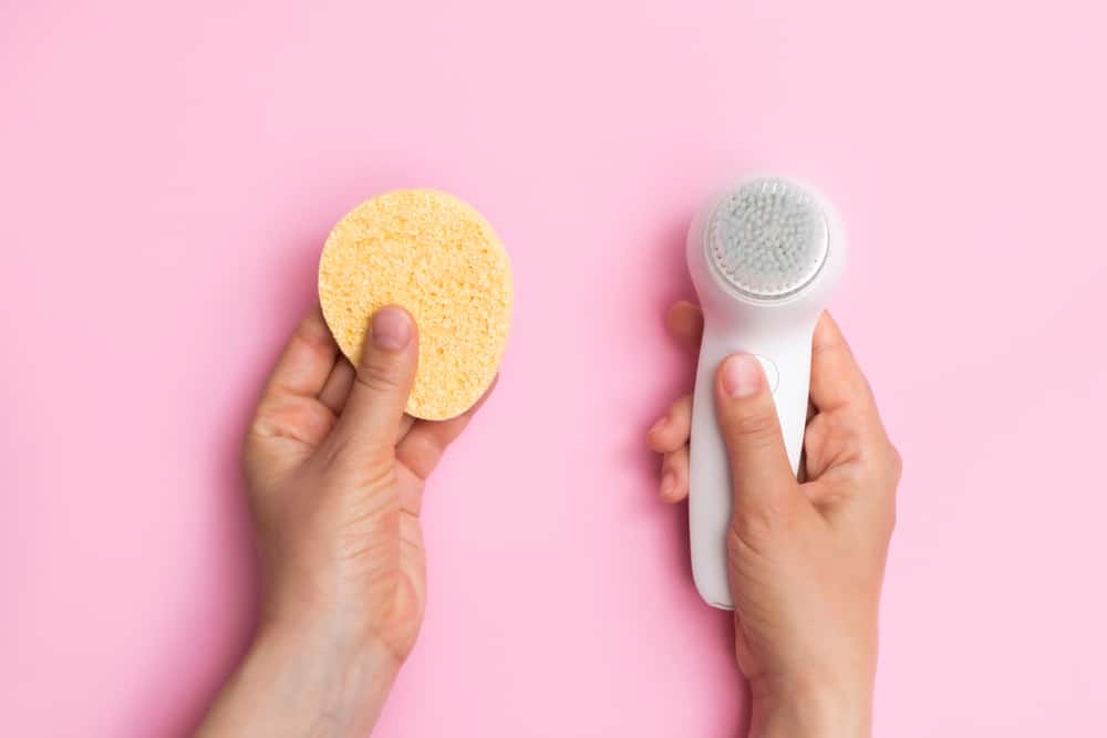 hands comparing facial brush and sponge