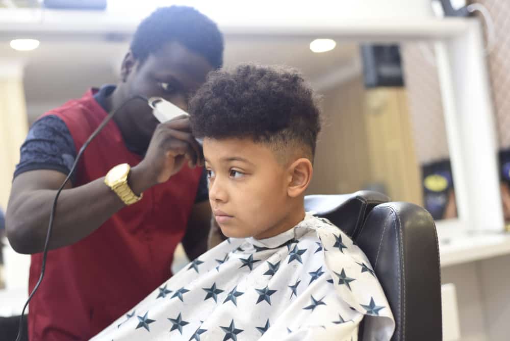 boy getting hair trimmed at Black barber