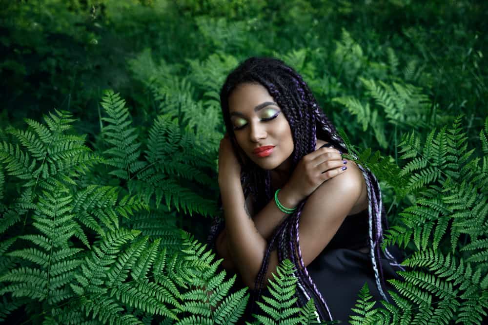 Woman sitting in fern forest with tree braids
