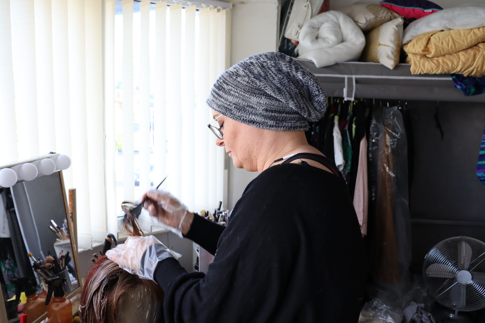 woman applies dye to a wig